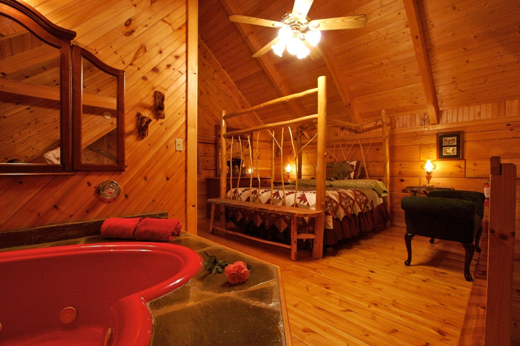 A wooden cabin interior with a four-poster bed, a red bathtub, and a ceiling fan.