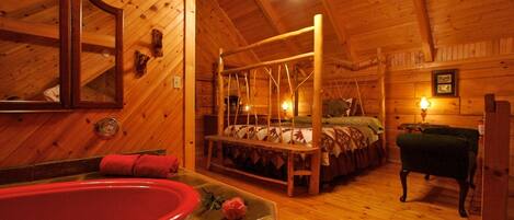 A wooden cabin interior with a four-poster bed, a red bathtub, and a ceiling fan.