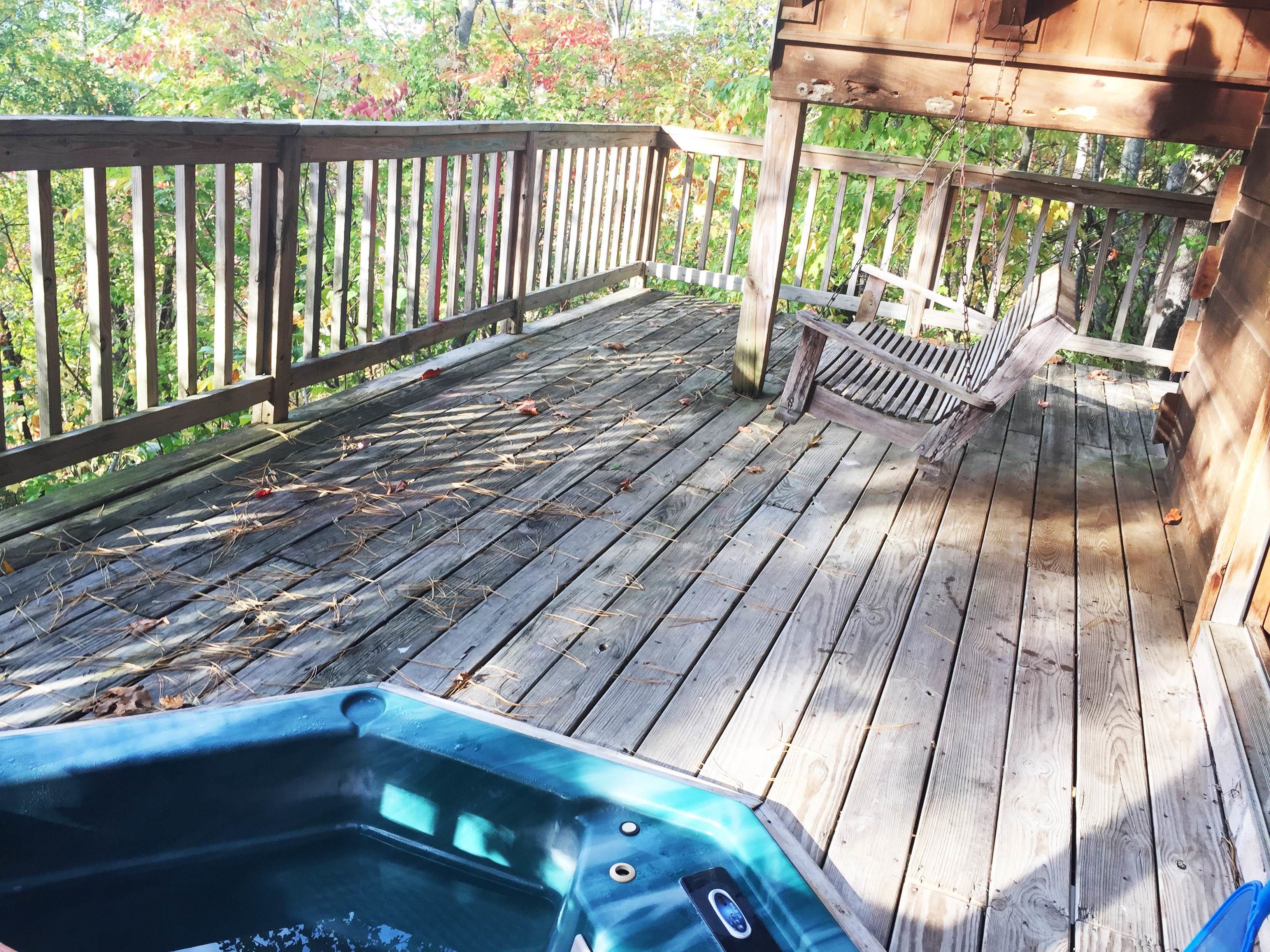 Eine Holzterrasse mit Whirlpool, Holzgeländern und einer Bank.