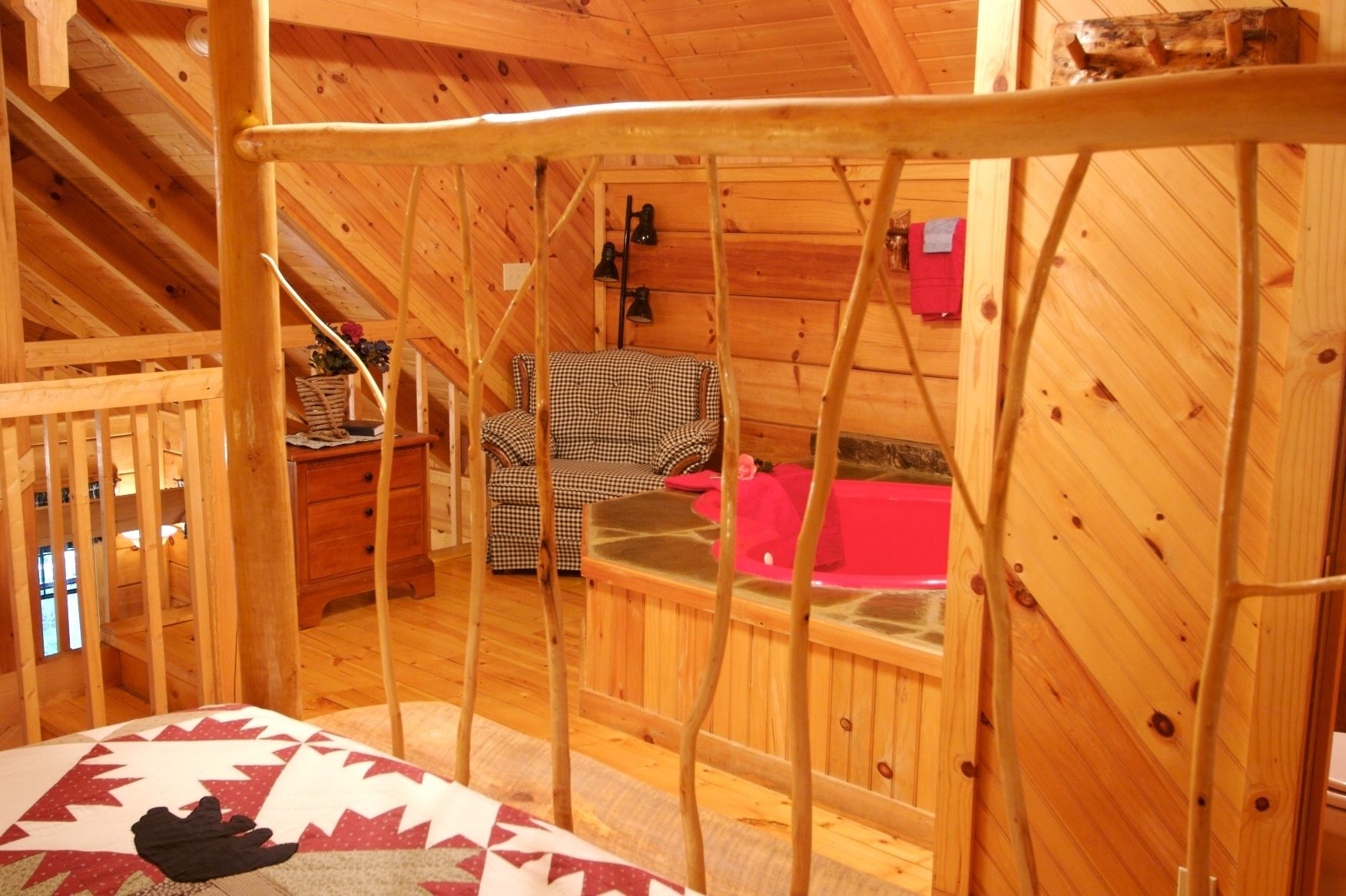 Ein gemütliches Blockhaus mit Holzinnenraum, einem karierten Sofa, einer roten Badewanne und einer Holzbalkendecke.
