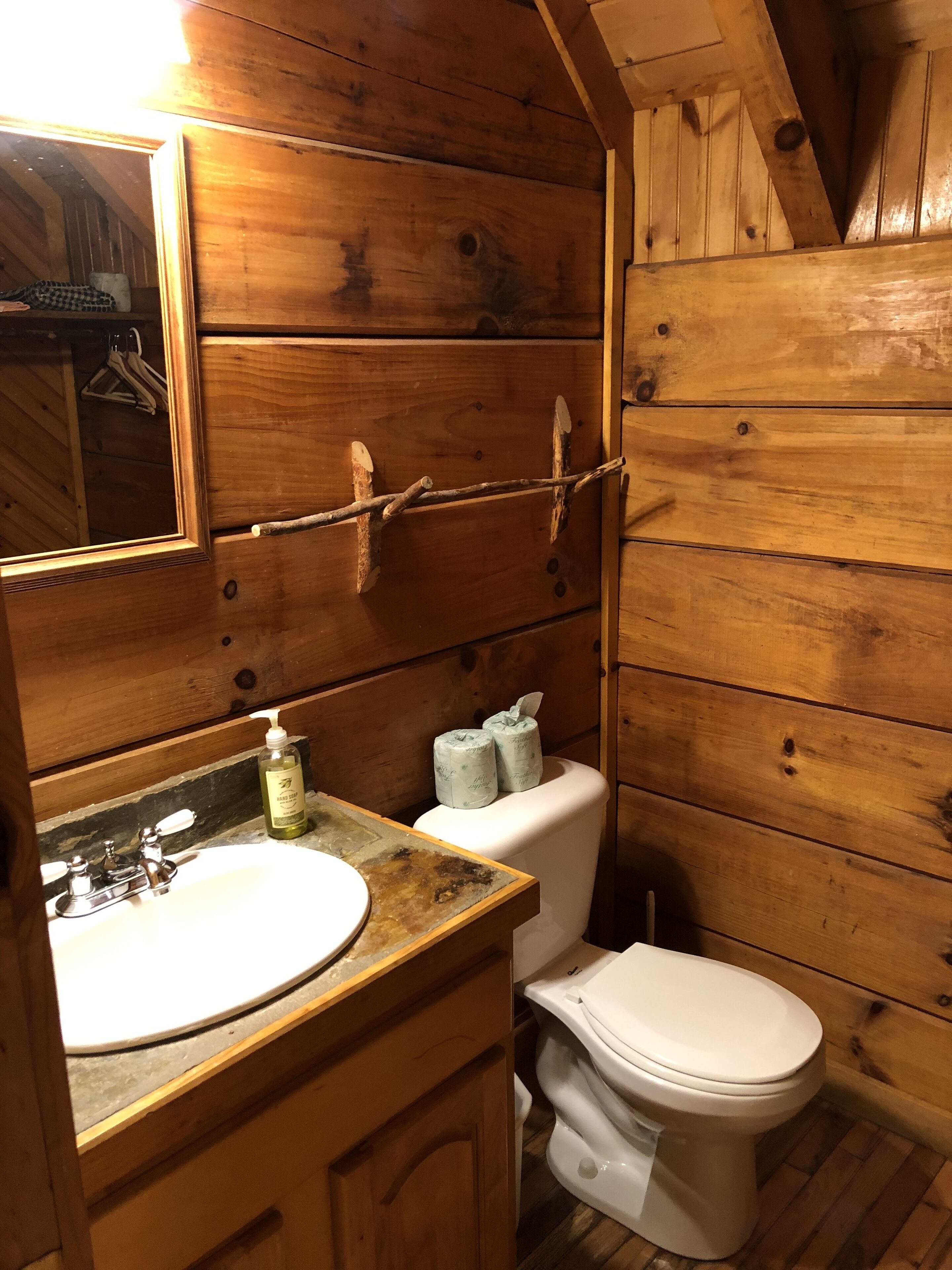 A wooden cabin bathroom with a wooden vanity, a white sink, and a toilet.