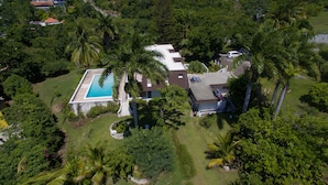 An aerial view of a residential property with a swimming pool, multiple houses, and lush greenery. - Burlingame Villa (Montego Bay)
