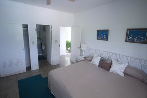 A bedroom with a bed, a nightstand, a lamp, and two framed pictures on the wall.