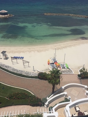 Une plage avec une eau cristalline, un rivage sablonneux et un kiosque.