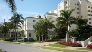 Un hôtel à plusieurs étages, doté d’une façade symétrique, de palmiers et d’une pelouse bien entretenue.