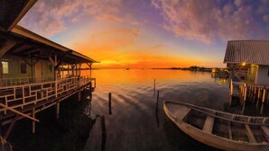 A waterfront property with a dock, a small boat, and a building with a balcony overlooking the water. - Saigon Bay Bed & Breakfast (Bocas del Toro)