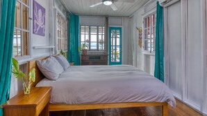 A bedroom with a wooden bed, a ceiling fan, and a view of the outside. - Saigon Bay Bed & Breakfast (Bocas del Toro)