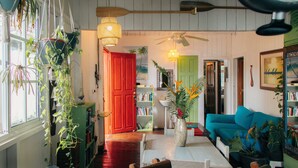 A cozy living room with a wooden floor, a green sofa, a white coffee table, and a red door. - Saigon Bay Bed & Breakfast (Bocas del Toro)