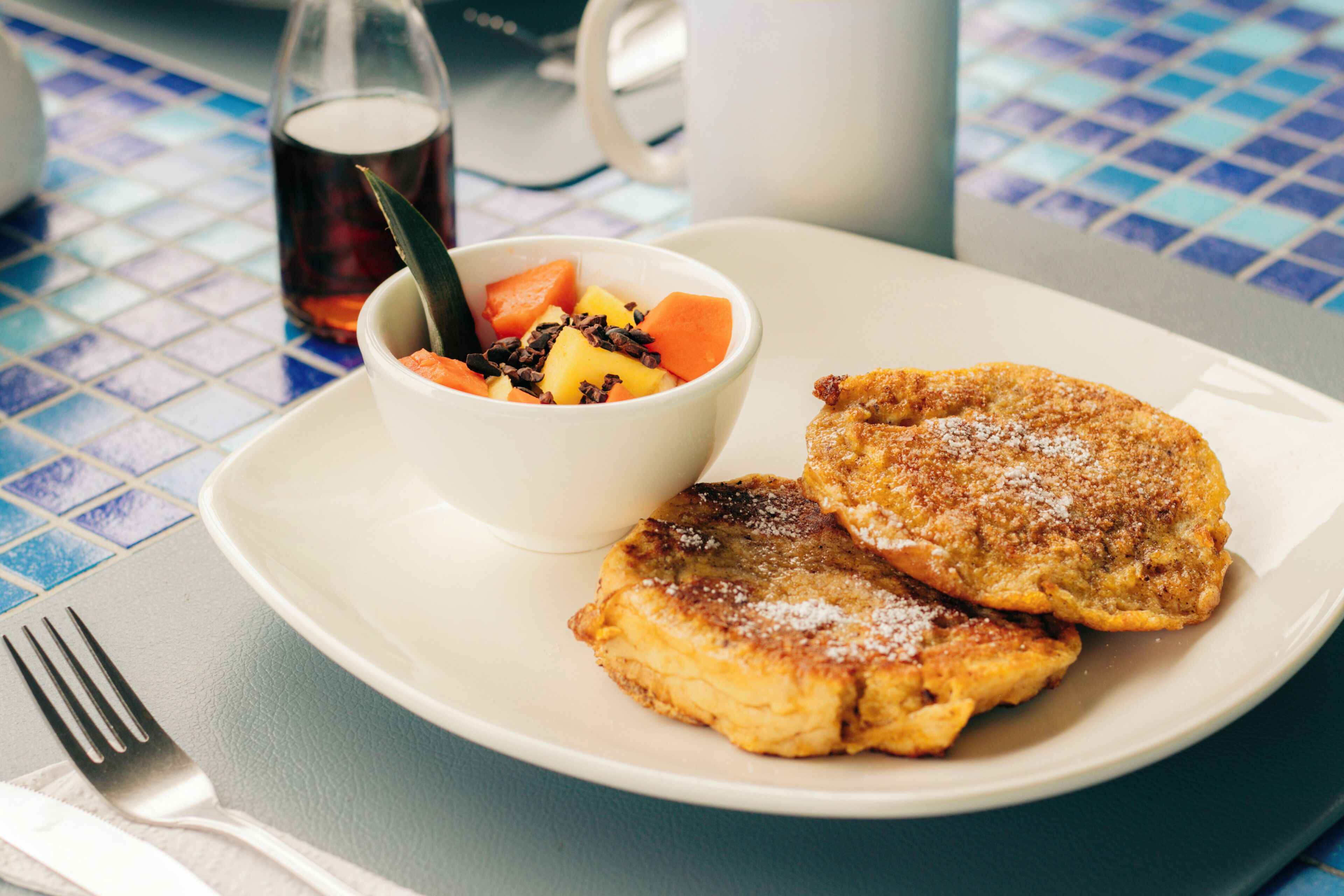 Un plato con dos tortitas y un tazón de ensalada de frutas.