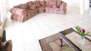 Ein großzügiger Wohnraum mit Holzbalkendecke, einem großen L-förmigen Sofa, einem Couchtisch und einem gemusterten Teppich.