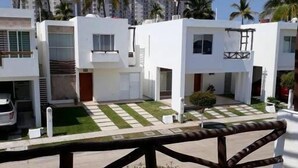 A modern residential area with white buildings, a paved driveway, and a wooden fence. - Casa Elena (Mazatlán)