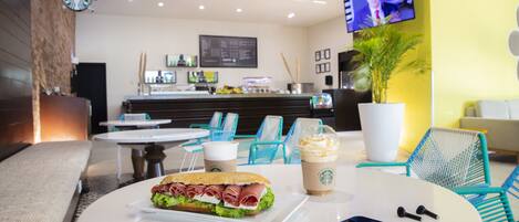 Una cafetería Starbucks con mesas, un sándwich, una bebida y un teléfono inteligente sobre la mesa.