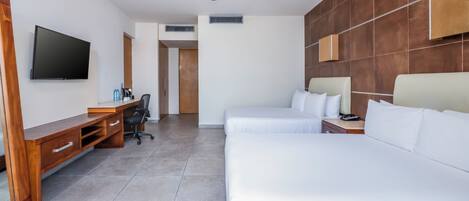 Una habitación de hotel con un escritorio de madera, un televisor de pantalla plana, una cama y un ventilador de techo.