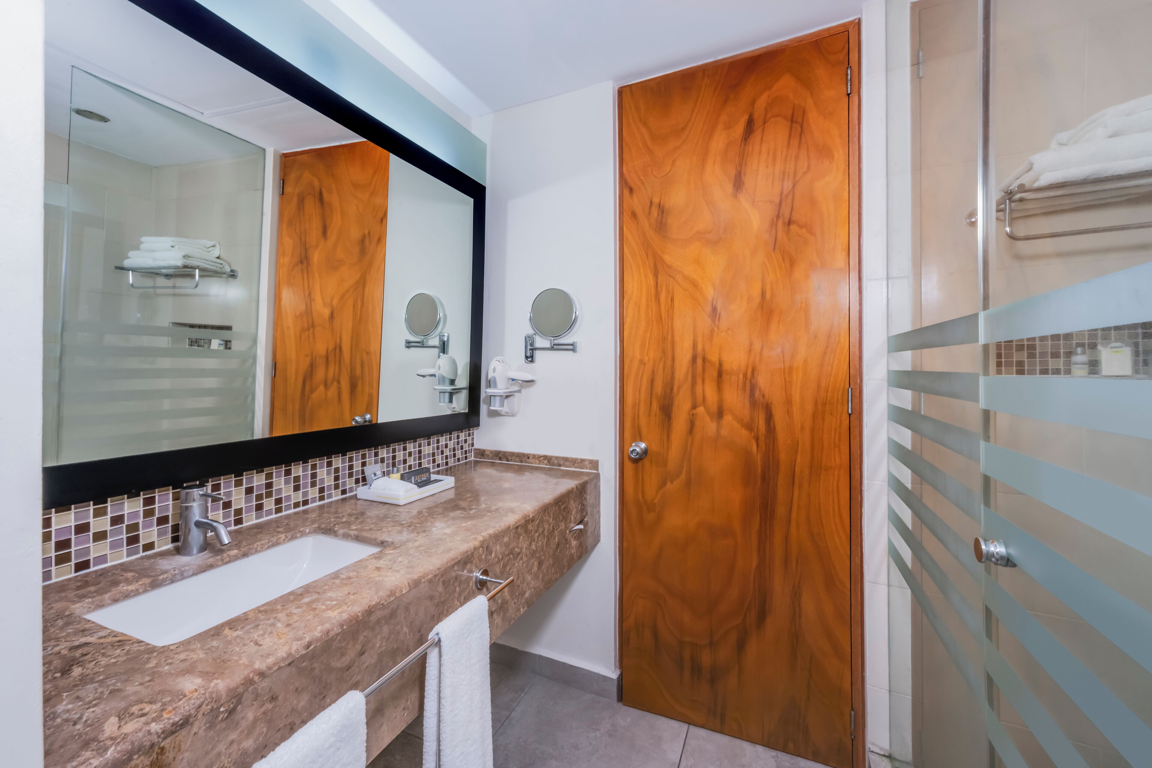 A bathroom with two sinks, a large mirror, and wooden doors.