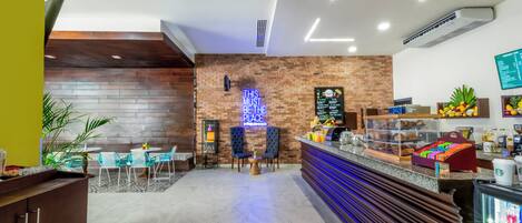 Un café moderno con pared de ladrillo, letrero de neón y una barra con pasteles.