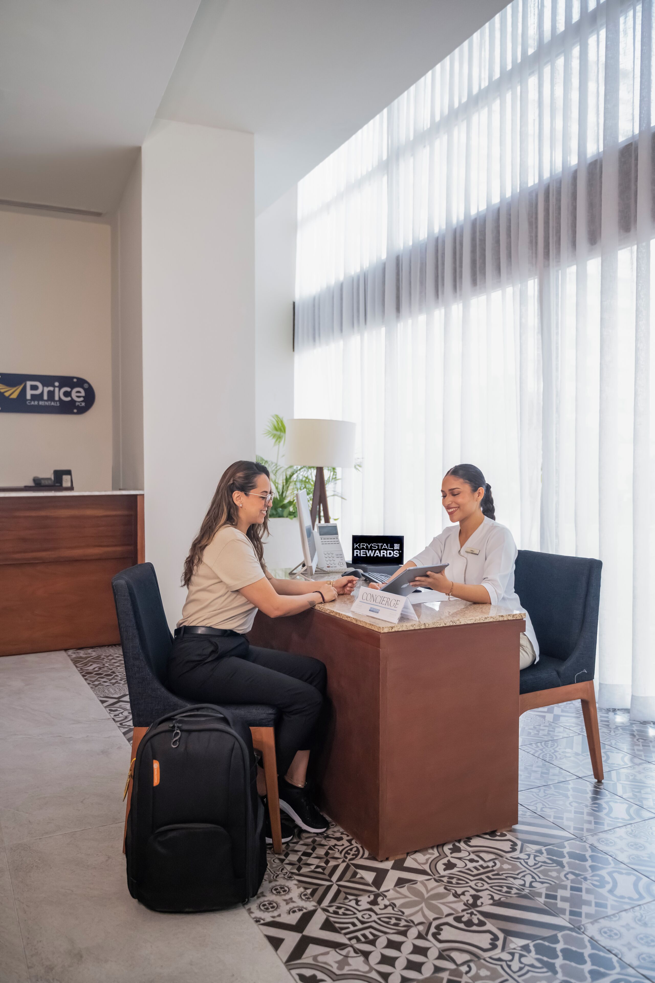 A reception desk with a sign for car rentals, a computer, and a name tag for a concierge.