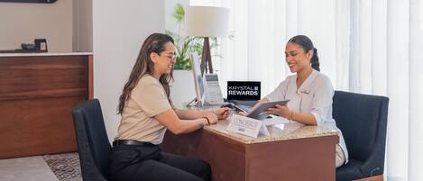 A reception desk with a sign for car rentals, a computer, and a name tag for a concierge.
