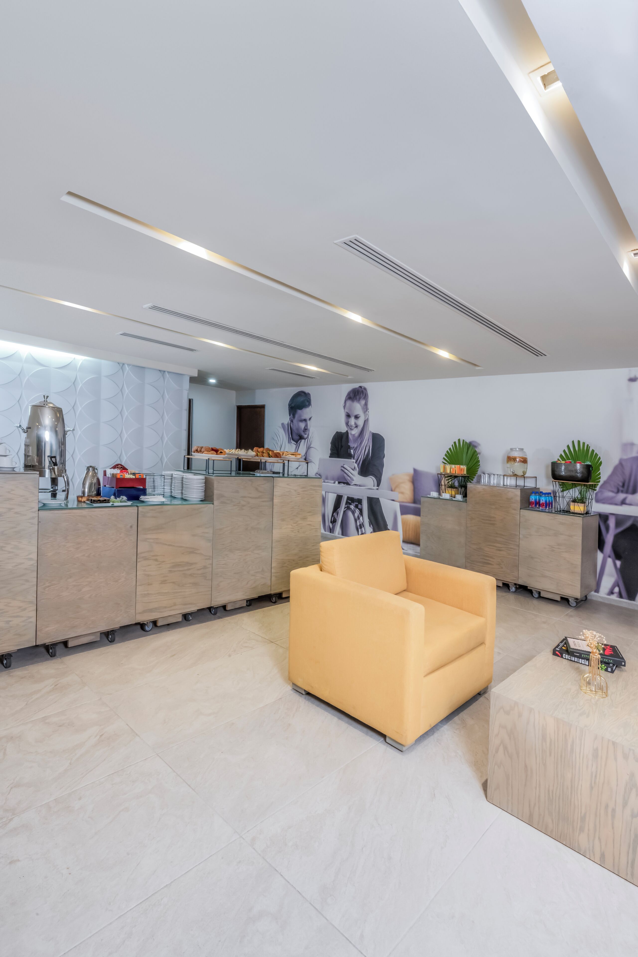 A modern hotel lobby with a reception desk, seating area, and a wall with a large portrait.