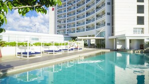 Una piscina al aire libre, sombrillas, sillones reclinables de piscina