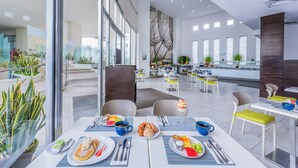 A modern dining area with tables set for breakfast, featuring plates of food, cutlery, and glasses. - Krystal Urban Cancun & Beach Club (Cancun)