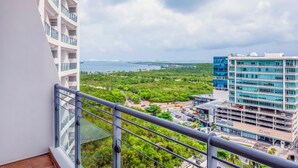 A high-rise building with multiple balconies overlooking a green landscape and a distant body of water. - Krystal Urban Cancun & Beach Club (Cancun)