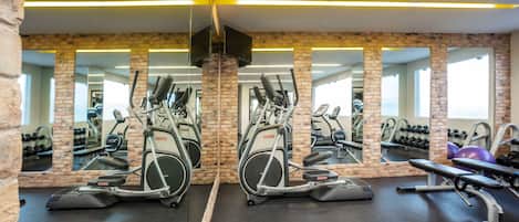 Un gimnasio con paredes de espejo, equipamiento de ejercicio y un diseño de pared de ladrillo.