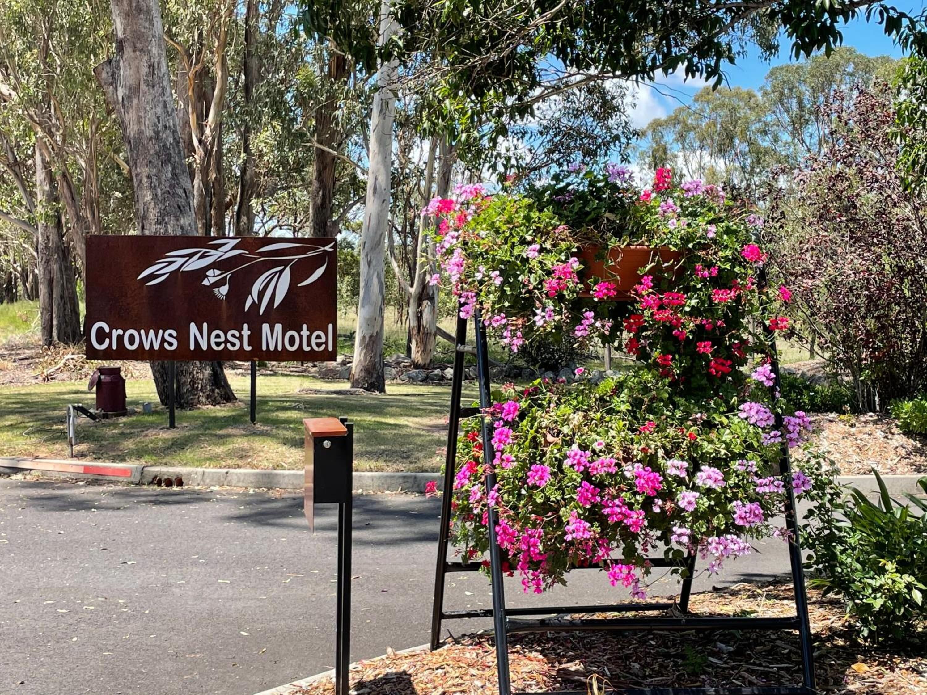 En skylt för Crows Nest Motel, med en blomsterarrangemang framför.