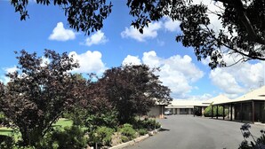 A hotel with a covered outdoor area, a parking lot, and a building with a flat roof.