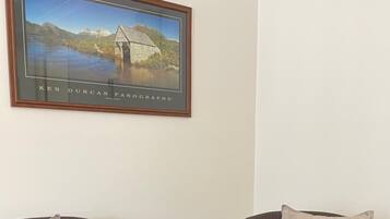 Two armchairs with cushions, a framed picture of a bridge, and a plain wall.