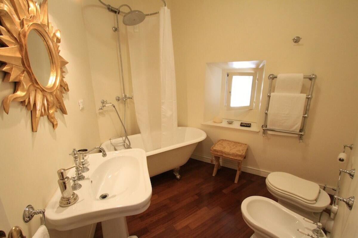 Un baño con una bañera independiente, un lavamanos, un inodoro y un mueble de tocador con espejo.