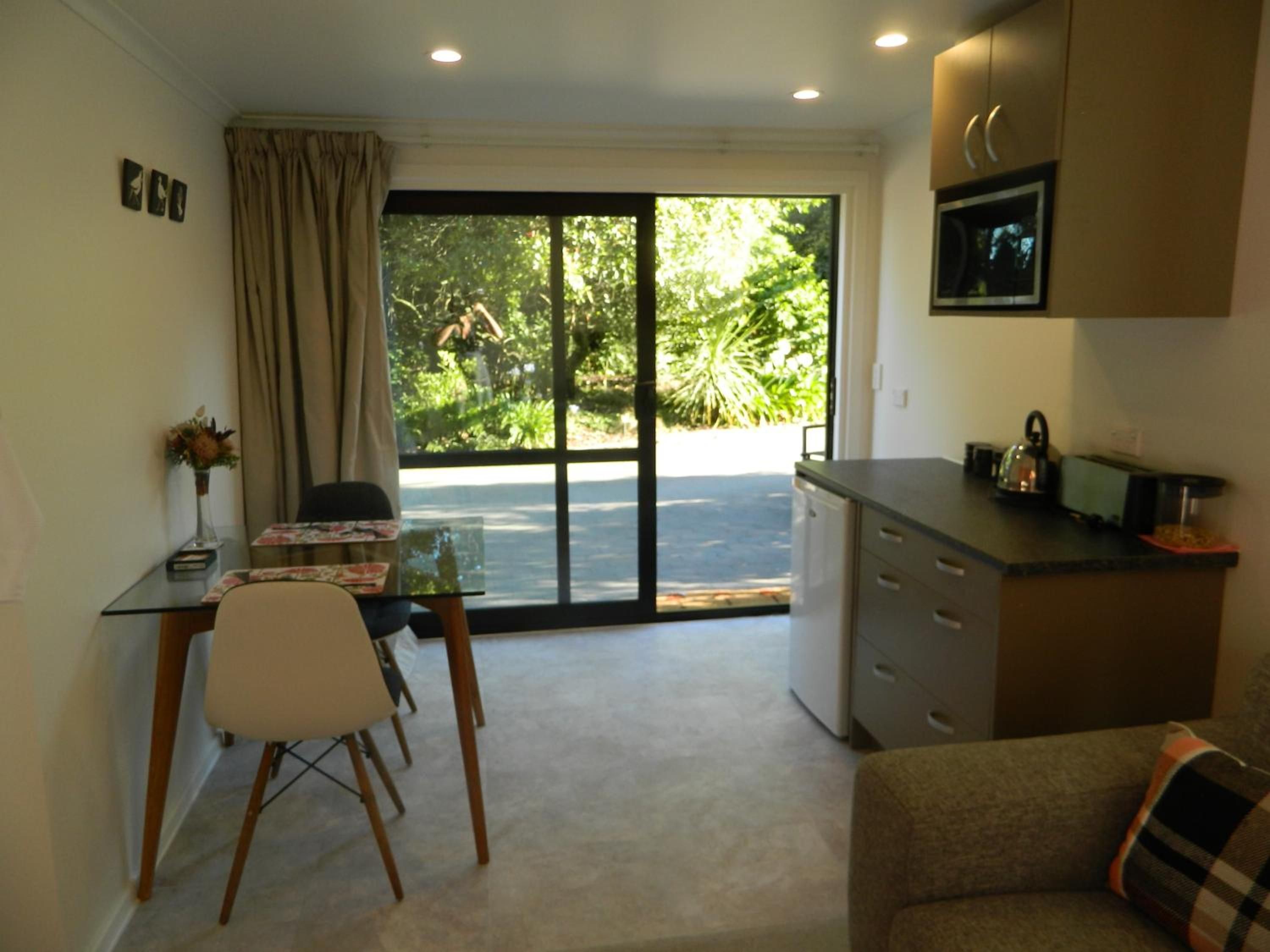 A compact living space with a dining area, kitchenette, and a sliding glass door leading to a garden.