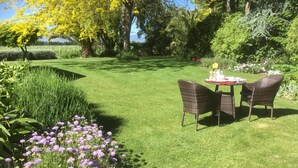 A well-maintained garden with a dining area featuring wicker chairs and a table set for two.