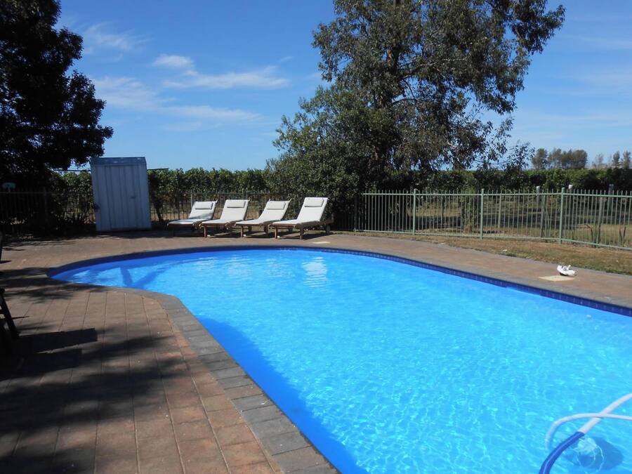 Piscina azul cristalina con sillas de descanso y un área cercada.
