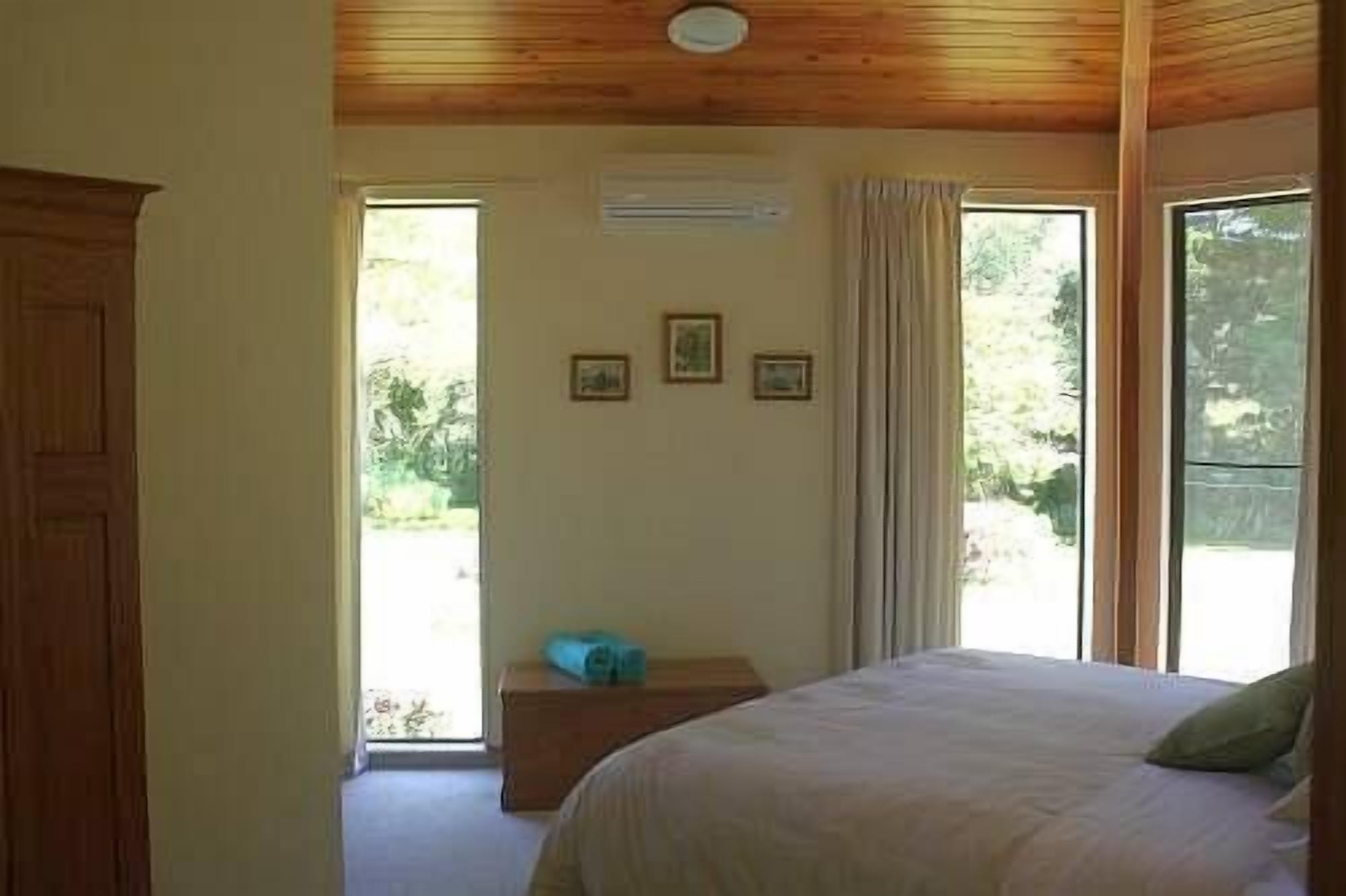 Une chambre à coucher avec un lit, un plafond en bois et une fenêtre avec des rideaux.