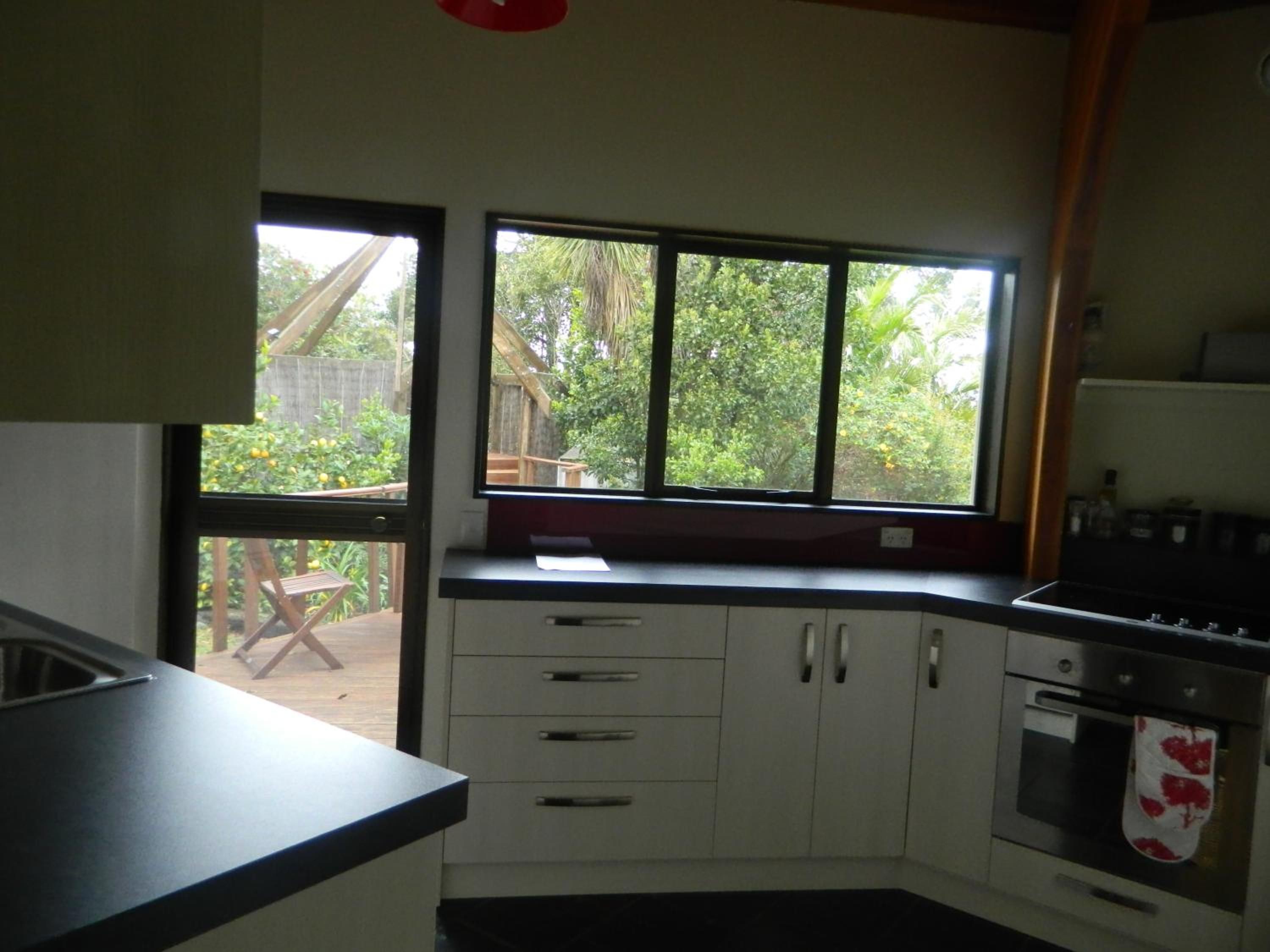 Una cocina con un amplio ventanal, muebles de madera, una encimera y un horno.