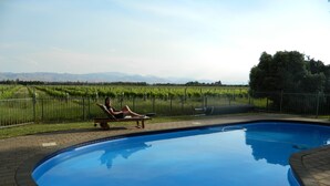 A swimming pool with a person relaxing on a lounge chair.