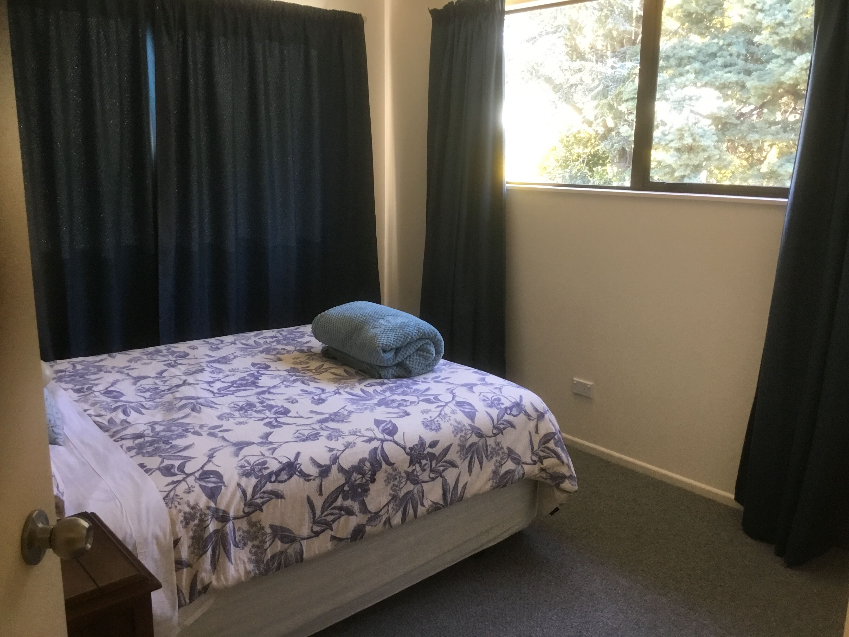 A bedroom with a bed, a window, and curtains.