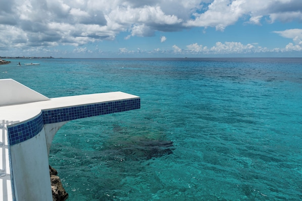 A clear blue sea with a white structure extending into the water.