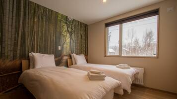 A hotel room with two beds, a large window, and a bamboo forest mural on the wall.