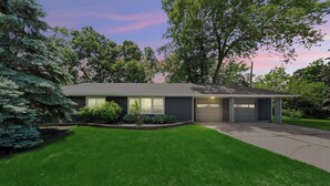 Une maison moderne à deux étages, dotée d’une pelouse bien entretenue, d’un garage et d’une allée.
