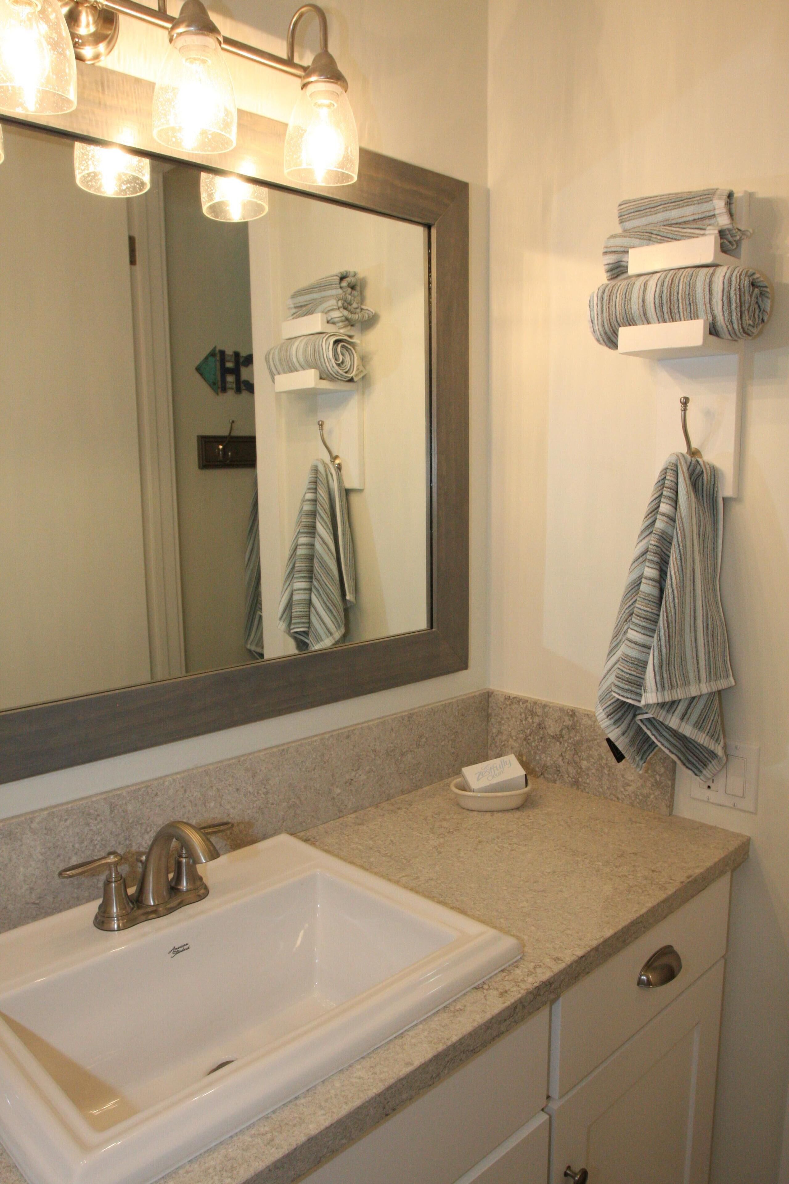 Une salle de bain équipée d’un lavabo, d’un miroir, d’un porte-serviettes et d’un distributeur de serviettes.