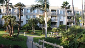 Hotel com vários andares e varandas, rodeado por vegetação exuberante e palmeiras.