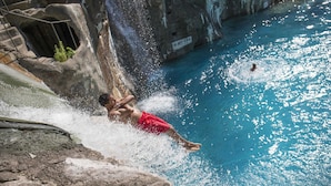 Una persona saltando desde un risco a una piscina.