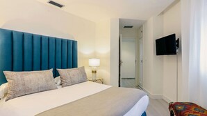 A hotel room with a bed, a TV, a lamp, and a chair.