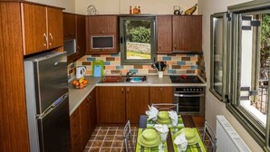 A compact kitchen with wooden cabinets, a built-in oven, and a window overlooking a garden. - #1-Clean, self catering 2 bedroom apartment with large balcony and free parking (Antipata)
