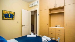 A hotel room with a bed, a wardrobe, a bathroom door, and a wall-mounted air conditioner. - #1-Clean, self catering 2 bedroom apartment with large balcony and free parking (Antipata)