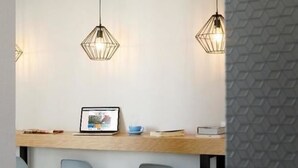 A modern office space with a wooden desk, a laptop, and three chairs.