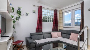 A modern living room with a sectional sofa, a glass coffee table, and a TV on a white stand. - Apartment in Arbanija with bubble bath (Trogir - Arbanija)