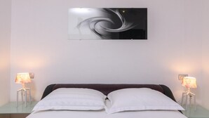 A bedroom with a bed, two bedside lamps, and a wall-mounted abstract art piece. - Apartment in Arbanija with bubble bath (Trogir - Arbanija)