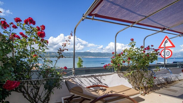 A terrace with a lounge chair, a view of the sea, and a speed limit sign. - Apartment in Arbanija with bubble bath (Trogir - Arbanija)